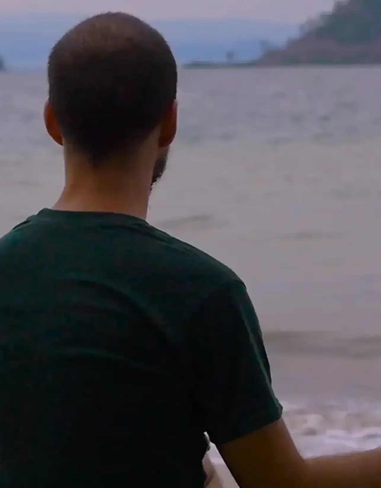 Person seated by the water in contemplation